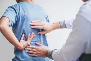 A chiropractor gently adjusting a client's mid-back while discussing symptoms in a quiet treatment room.